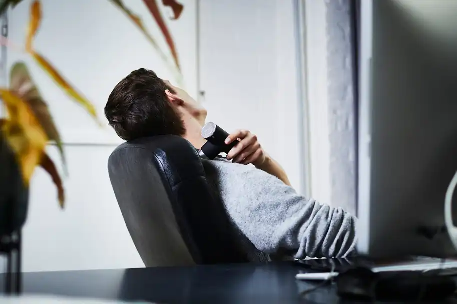 Mann wendet im Büro Massagepistole an der Schulter an