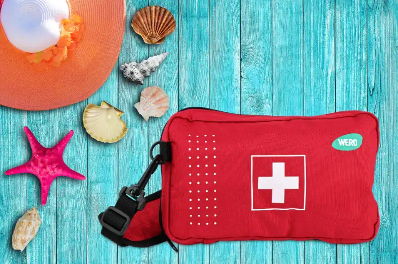 Reiseapotheke-Tasche mit Muscheln und Sonnenhut auf blauen Brettern
